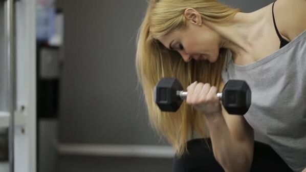 La fille effectue un exercice avec des haltères